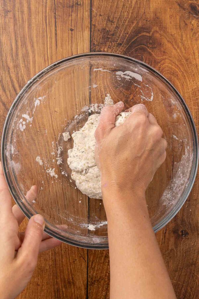 A hand forming cracker dough into a ball.