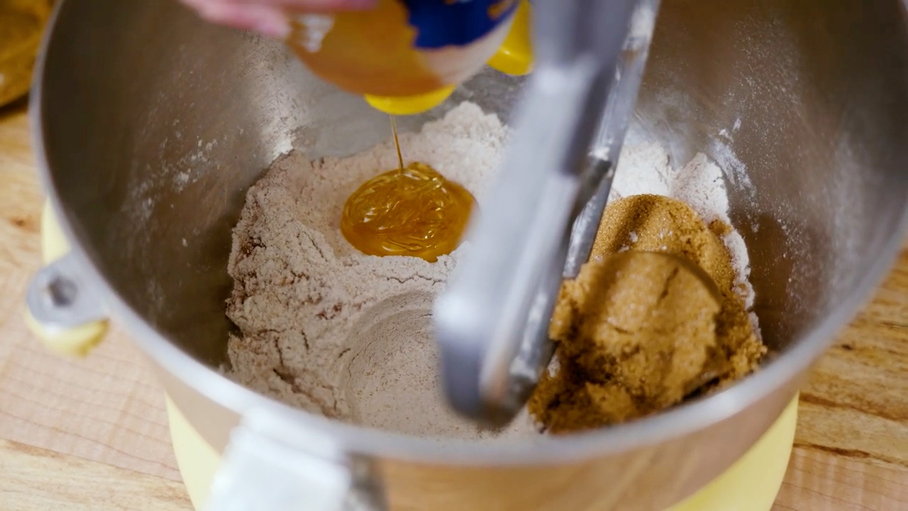 Wet ingredients being added to dry ingredients for homemade graham crackers.