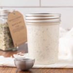 A jar of homemade buttermilk ranch sitting on a counter.