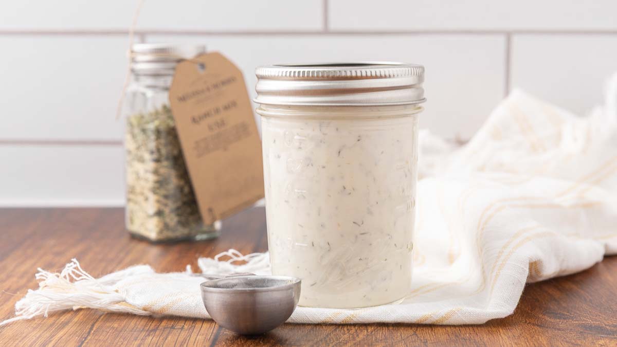 A jar of homemade buttermilk ranch sitting on a counter.