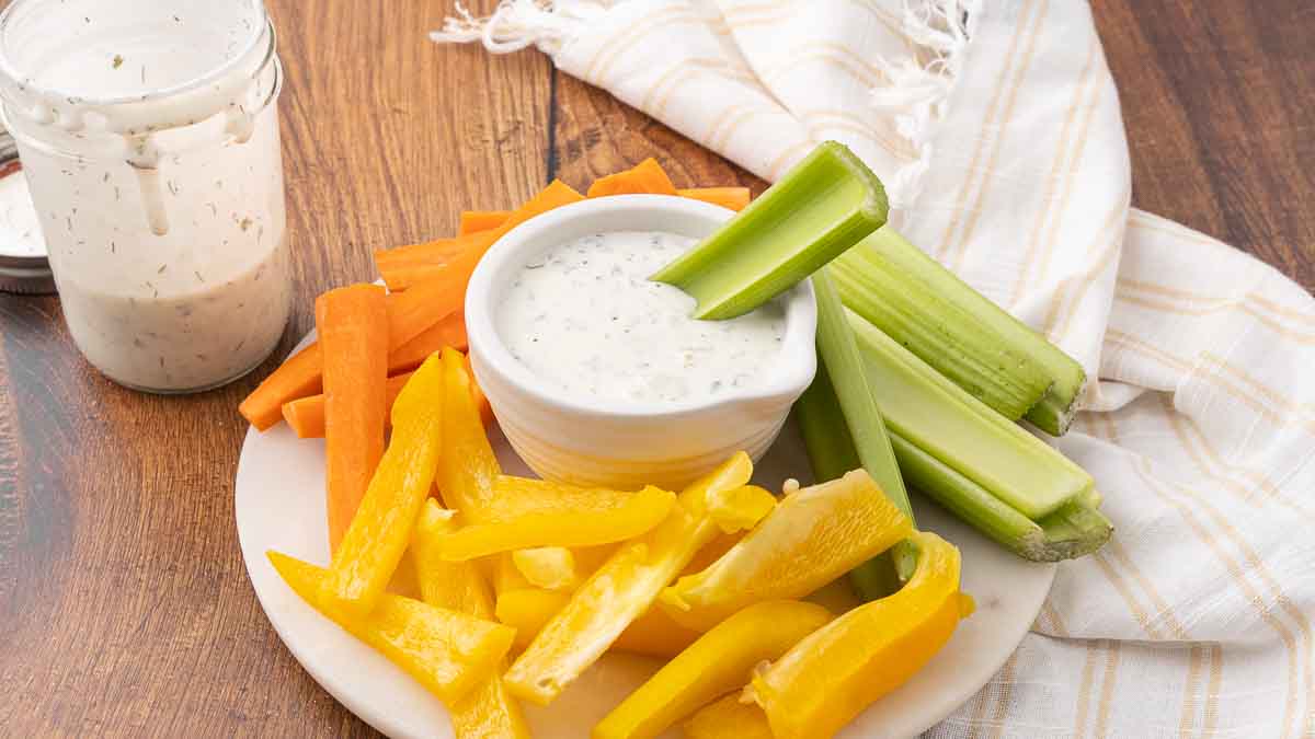 A platter of veggies circled around a bowl of homemade buttermilk ranch dressing.