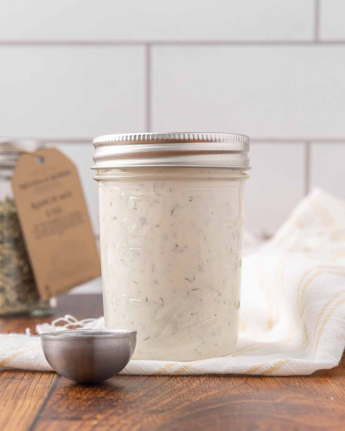 A jar of homemade buttermilk ranch sitting on a counter.