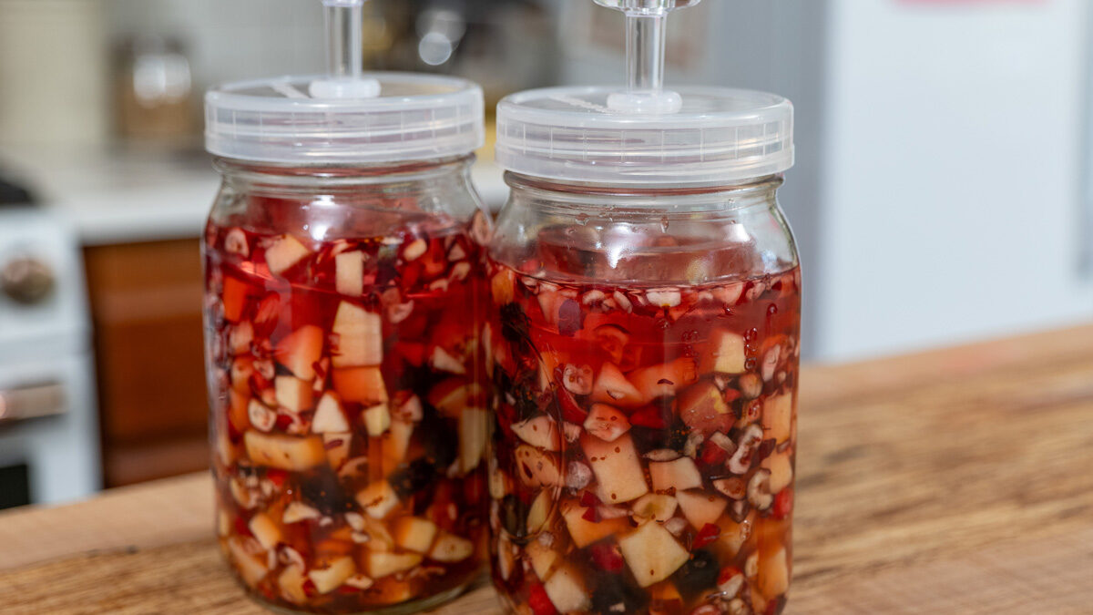 Two jars of cranberry sauce fermenting with airlock lids.