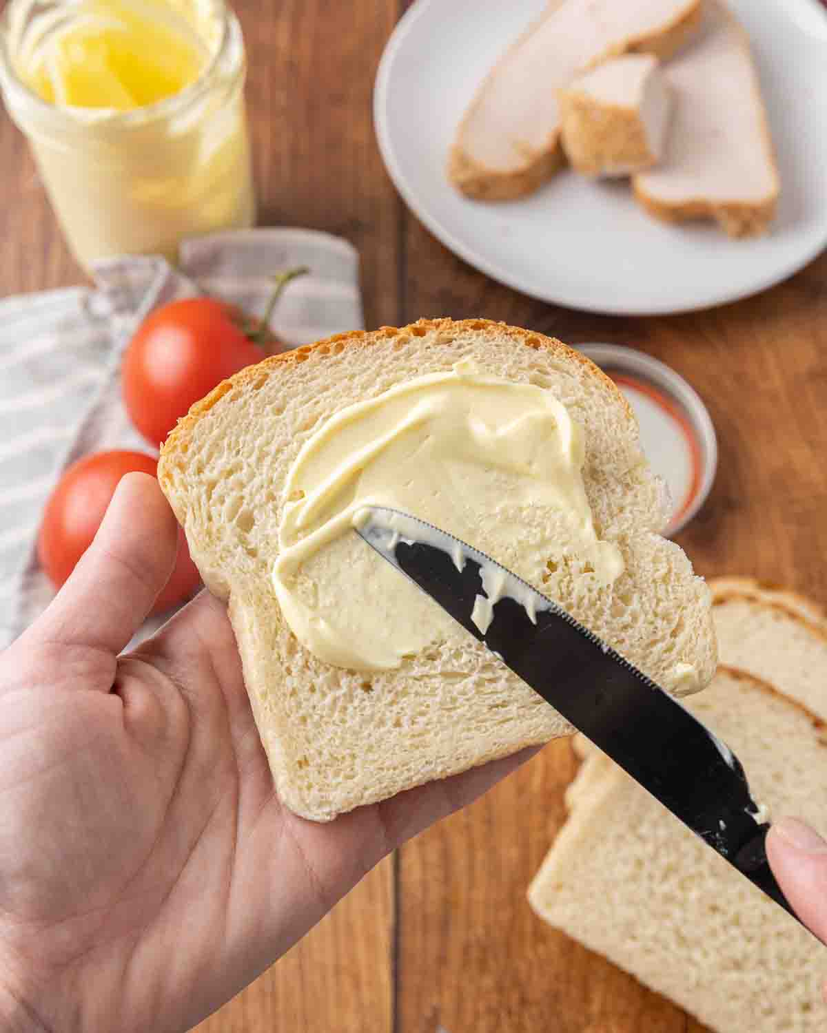 A knife spreading homemade mayonnaise on a slice of bread.