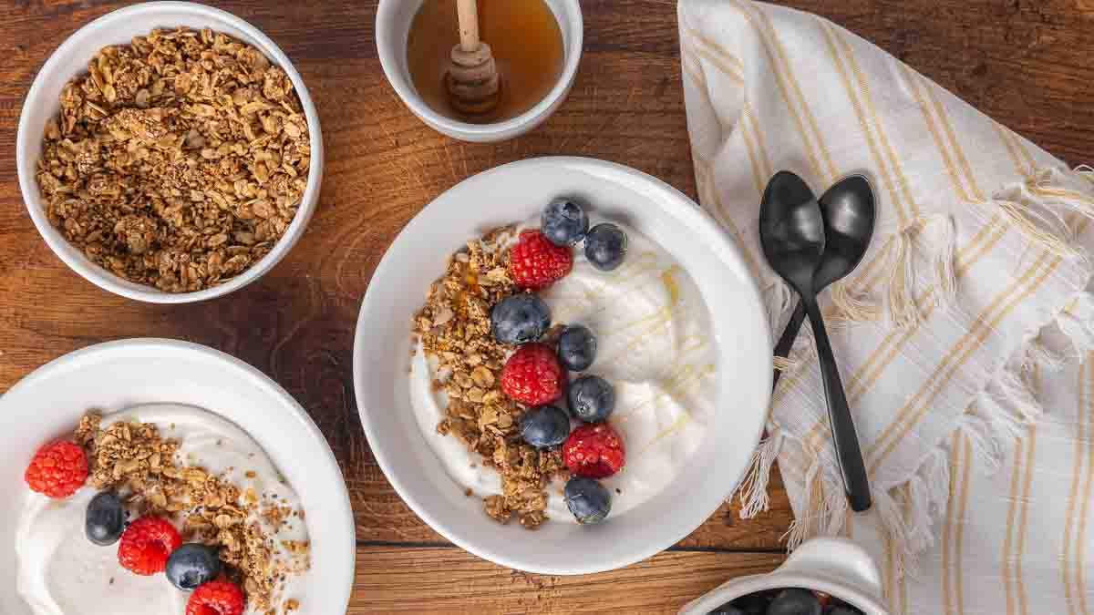 A bird's eye view of a bowl filled with homemade yogurt, and topped with granola and fresh berries.