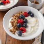 A bowl filled with homemade yogurt, and topped with granola and fresh berries.