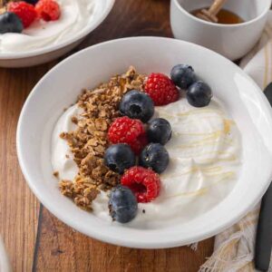 A bowl filled with homemade yogurt, and topped with granola and fresh berries.