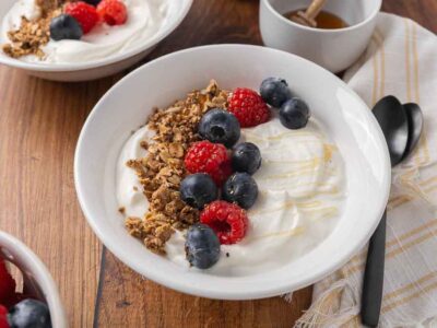 A bowl filled with homemade yogurt, and topped with granola and fresh berries.
