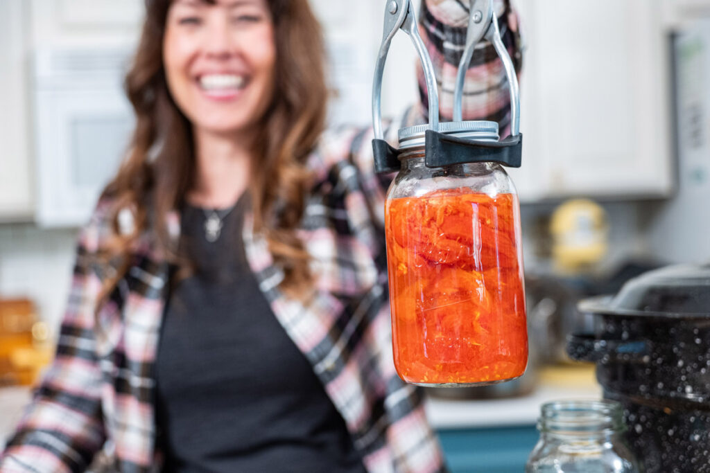 A woman holding up a jar of canned food.