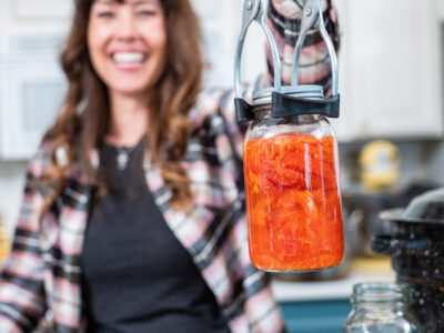 A woman holding up a jar of canned food.