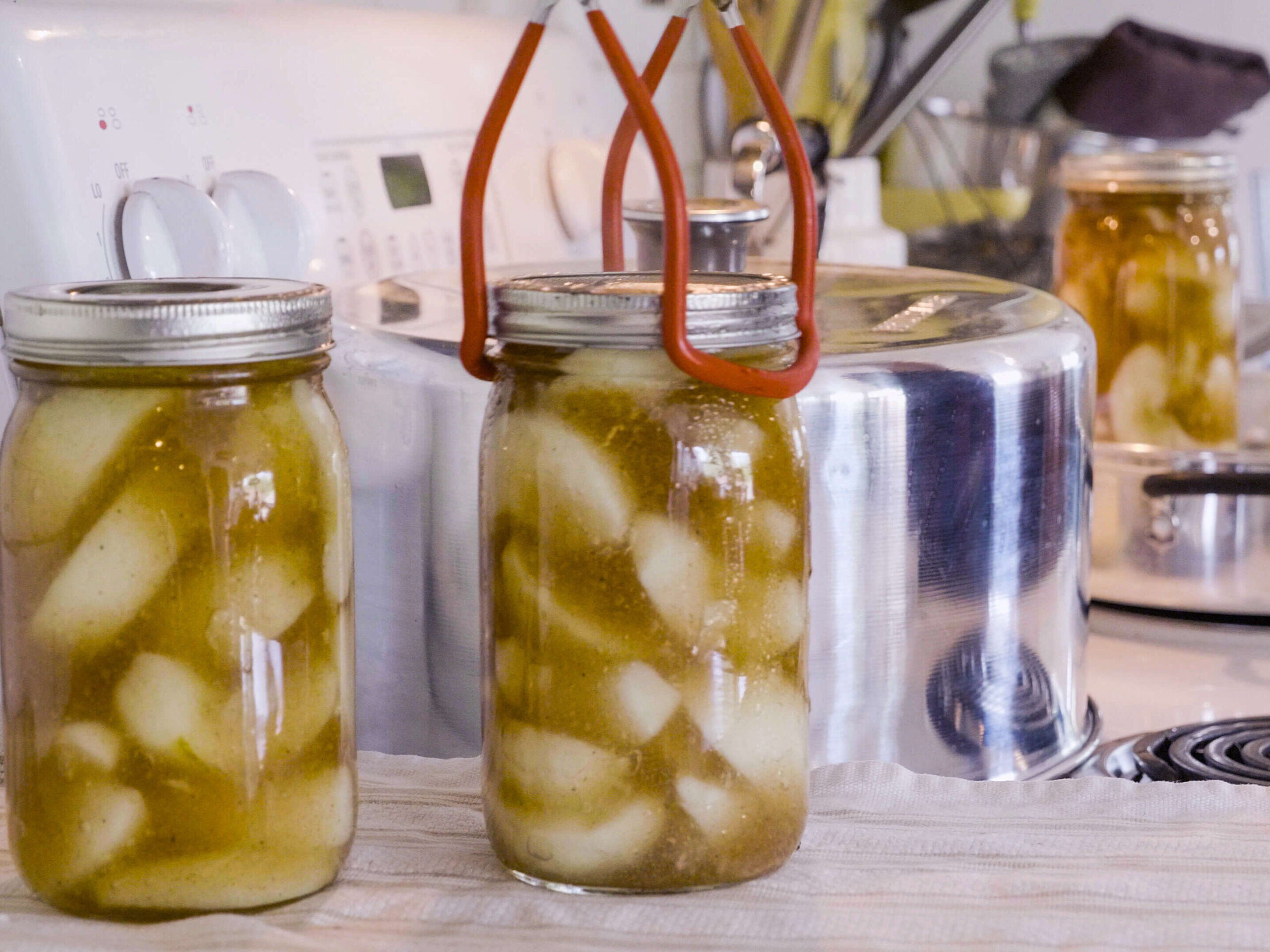 A jar lifter setting a jar of canned apple pie filling onto the counter.