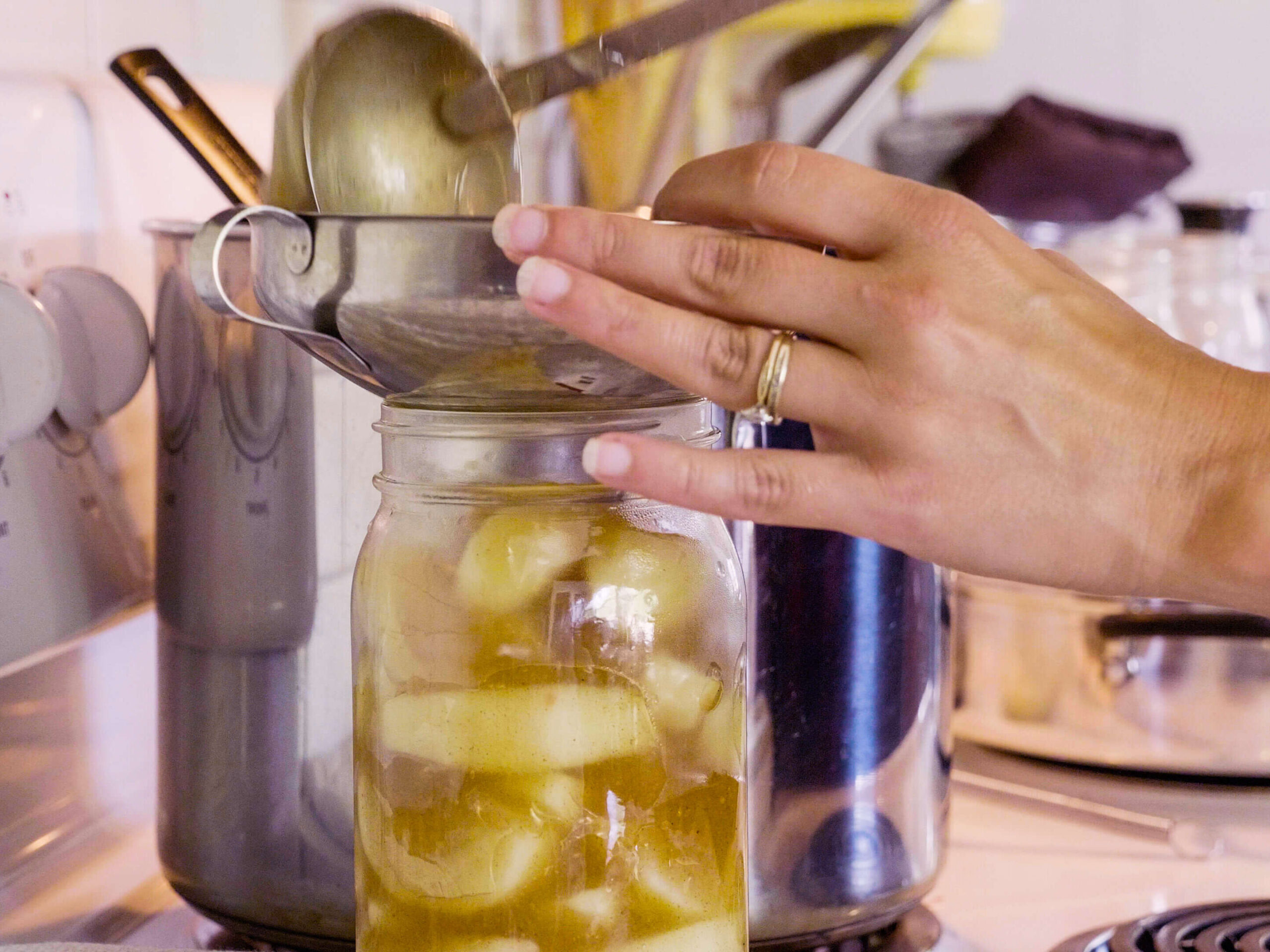 A woman ladling apple pie filling into a mason jar.