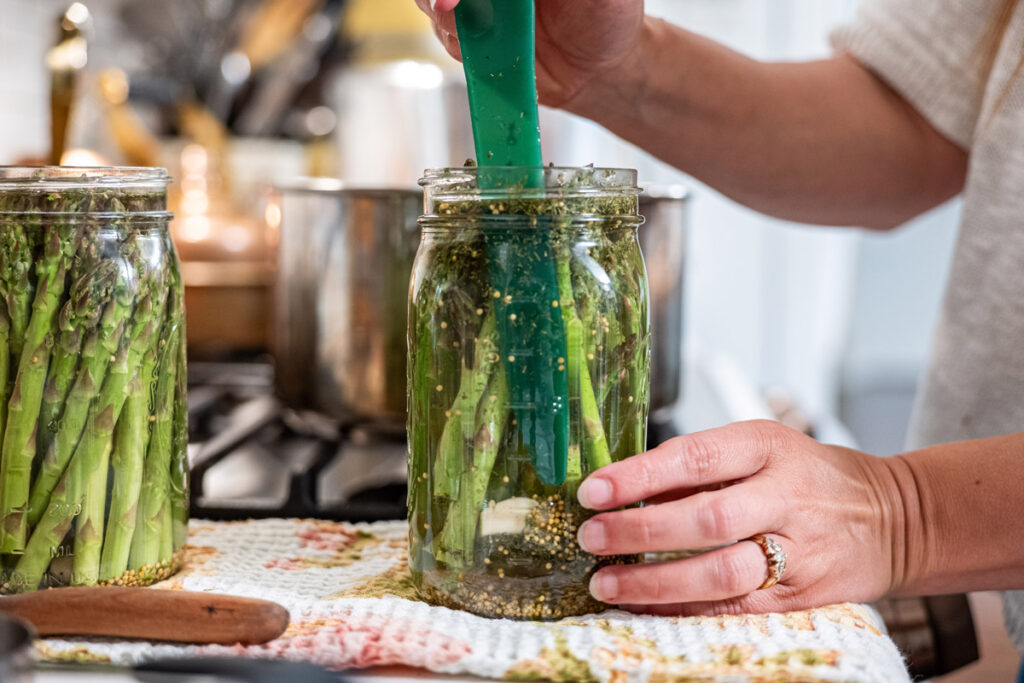 A bubble remover tool in a jar of pickled asparagus.