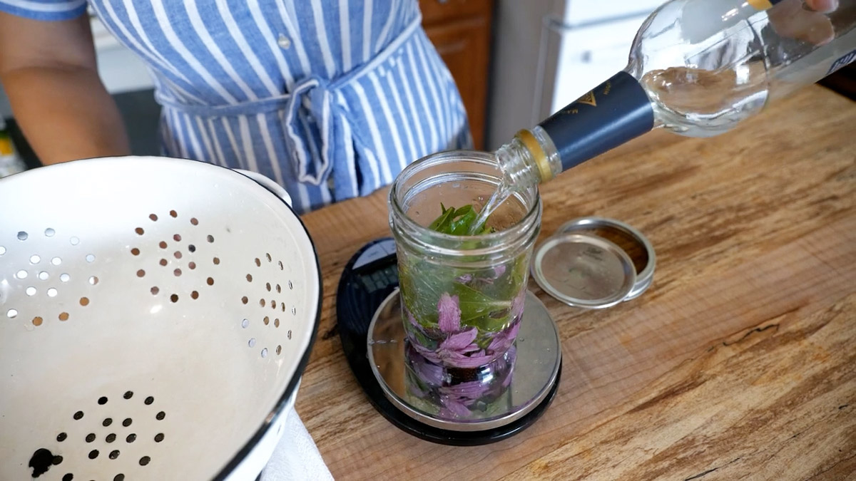 Pouring vodka over echinacea leaves and flowers.