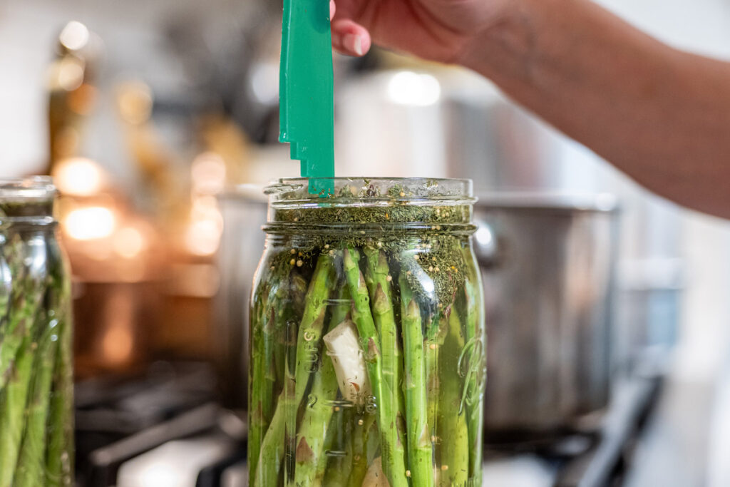 A jar of pickled asparagus and a headspace measuring tool.