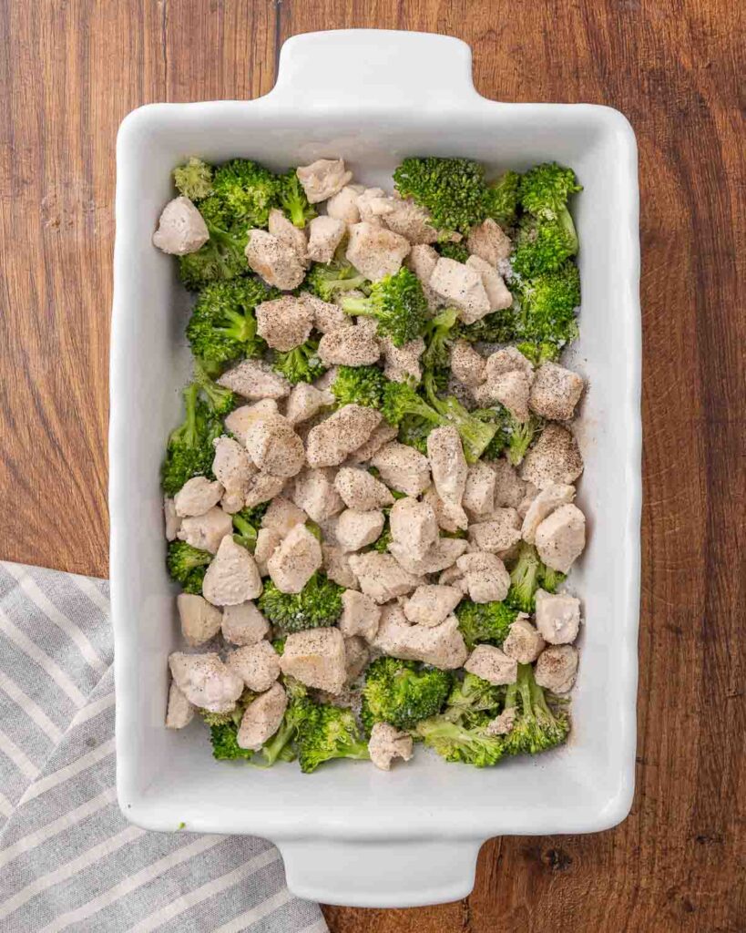 Cooked chicken and broccoli arranged in a 9X13 pan.
