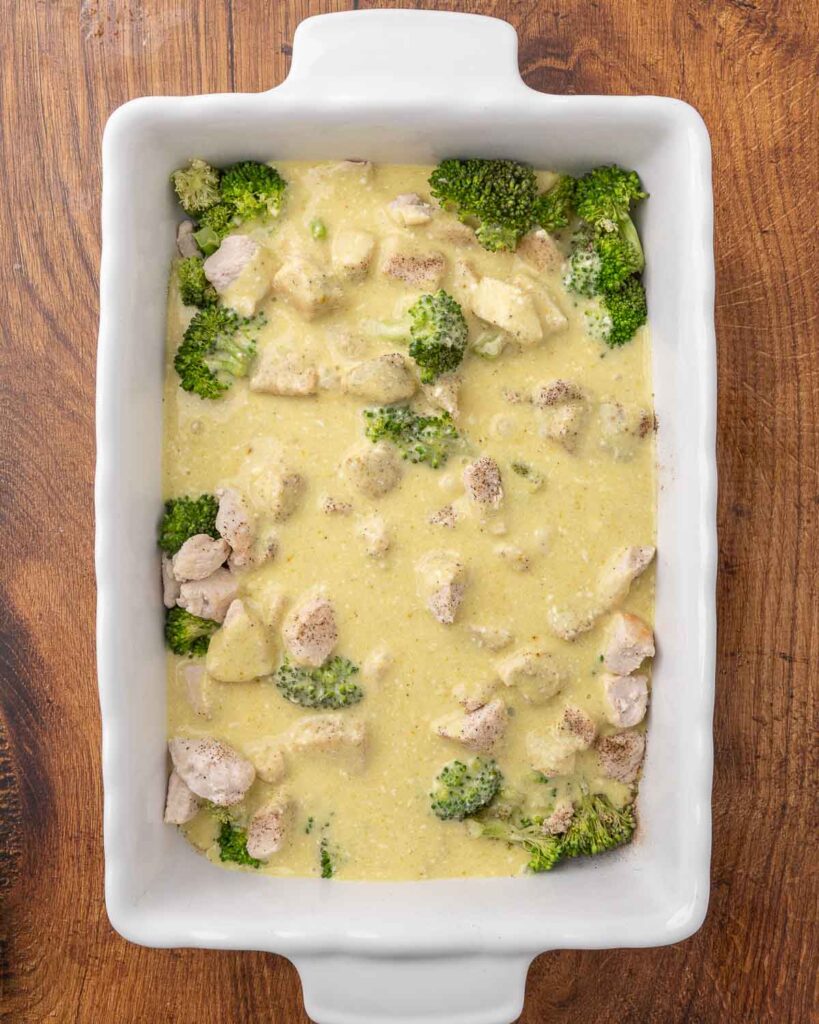Creamy curry sauce poured over broccoli and chicken in a 9x13 pan.
