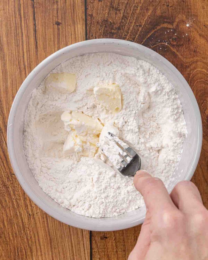 A fork cutting butter into jam roly poly dry ingredients.