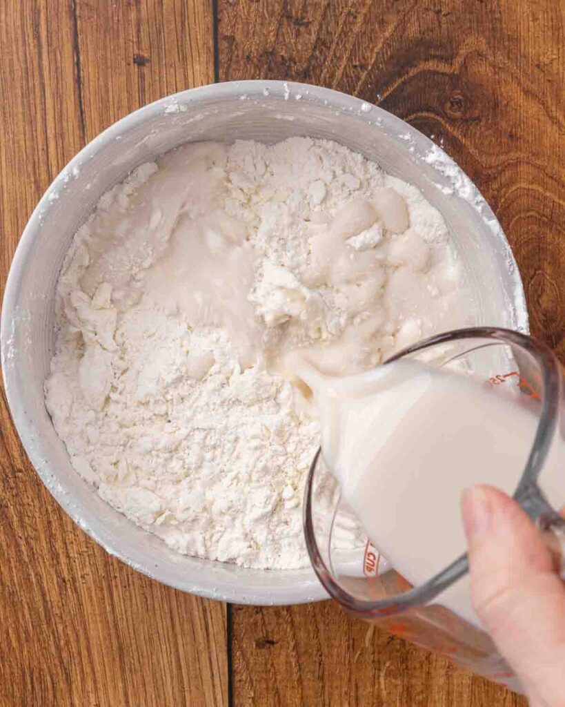 Adding milk to jam roly poly dry ingredients.
