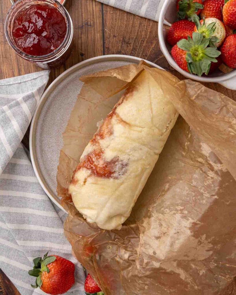 Removing a jam roly poly from parchment paper.