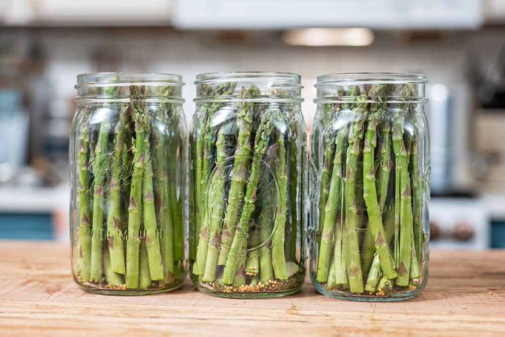Jars of asparagus on a counter.