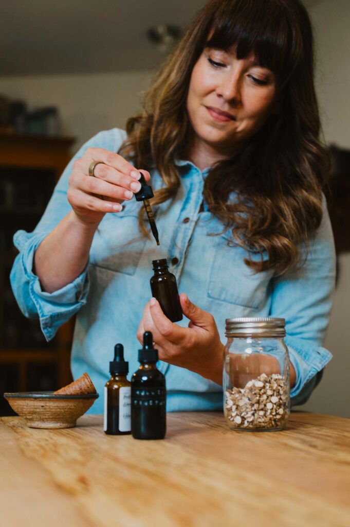 A woman with homemade herbal tinctures on a counter.