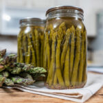 Jars of canned pickled asparagus on a counter.