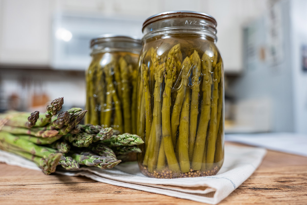 Jars of canned pickled asparagus on a counter.