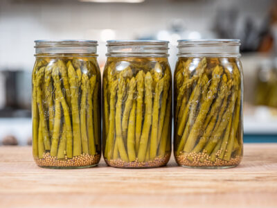 Jars of canned pickled asparagus on a counter.