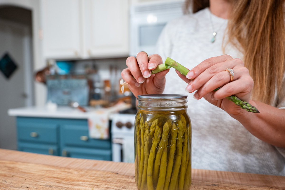 A woman snapping a fresh spear of asparagus.