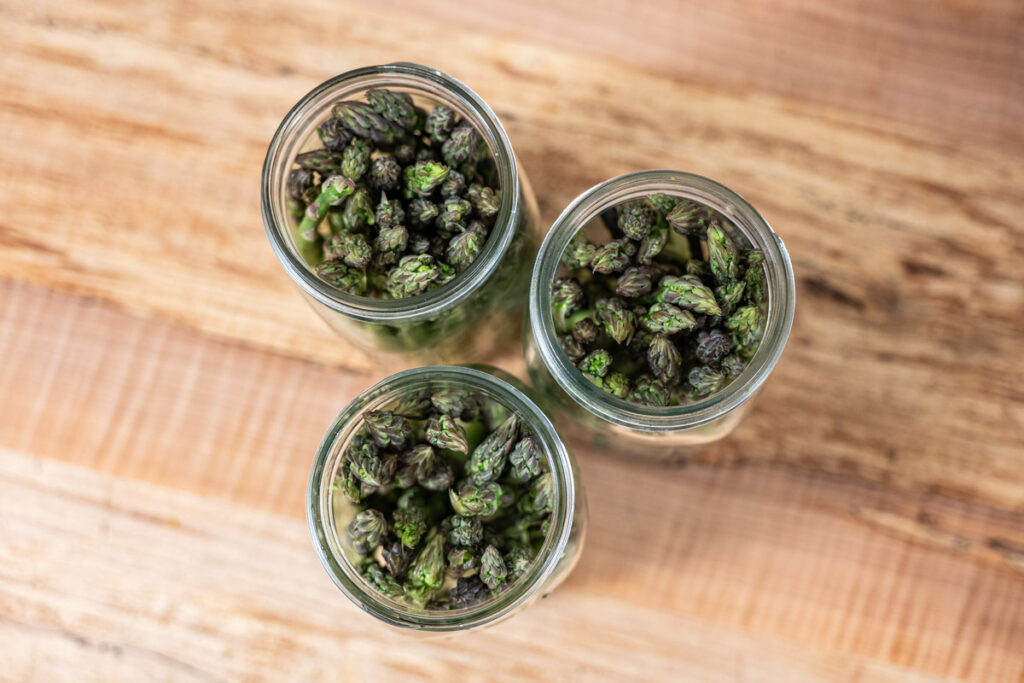 Overhead look into three jars of pickled asparagus.