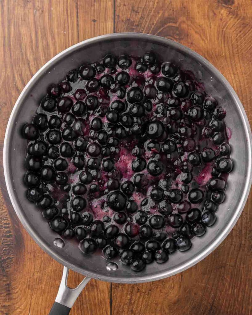 A bird's eye view of a skillet filled with blueberry sauce ready for dumplings to be added.