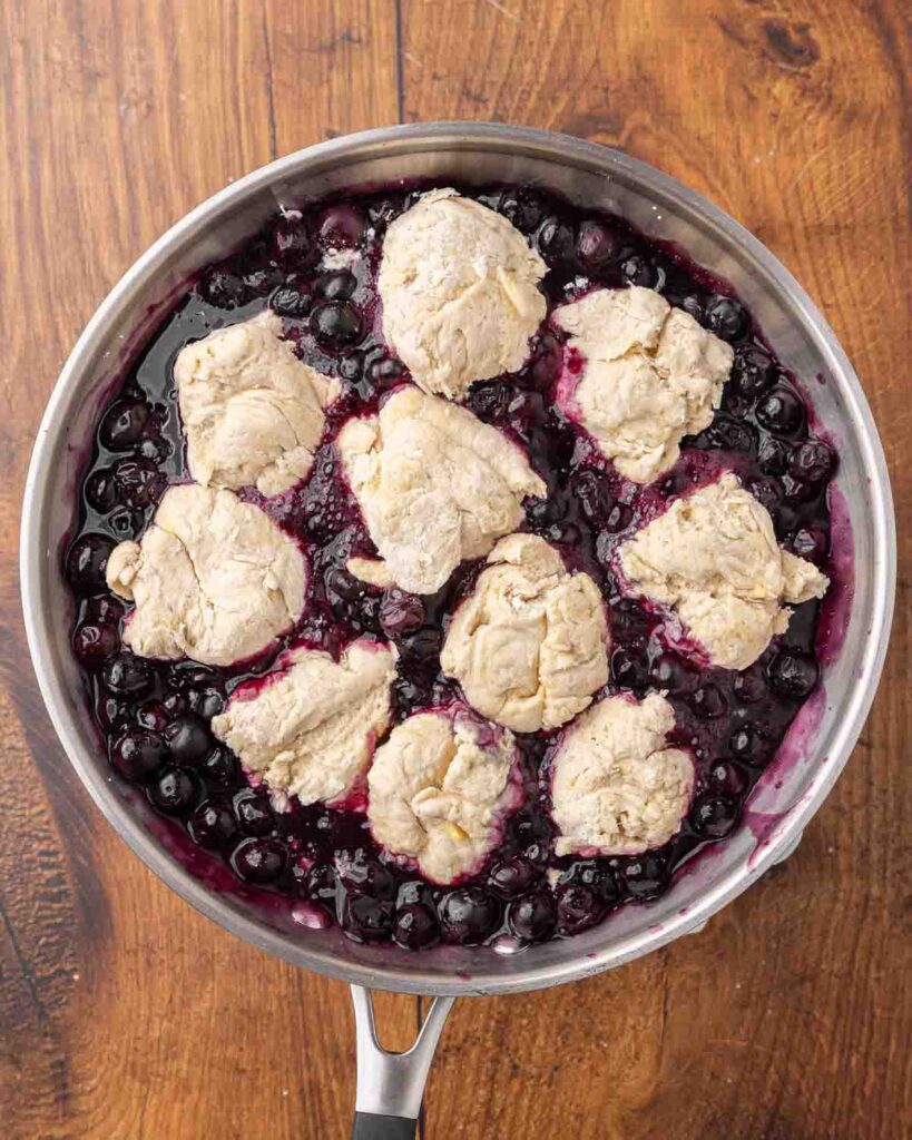 Birdseye view of a skillet filled with blueberry dumplings ready to cook.