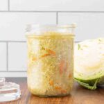 A jar of fermented sauerkraut sitting on a counter.
