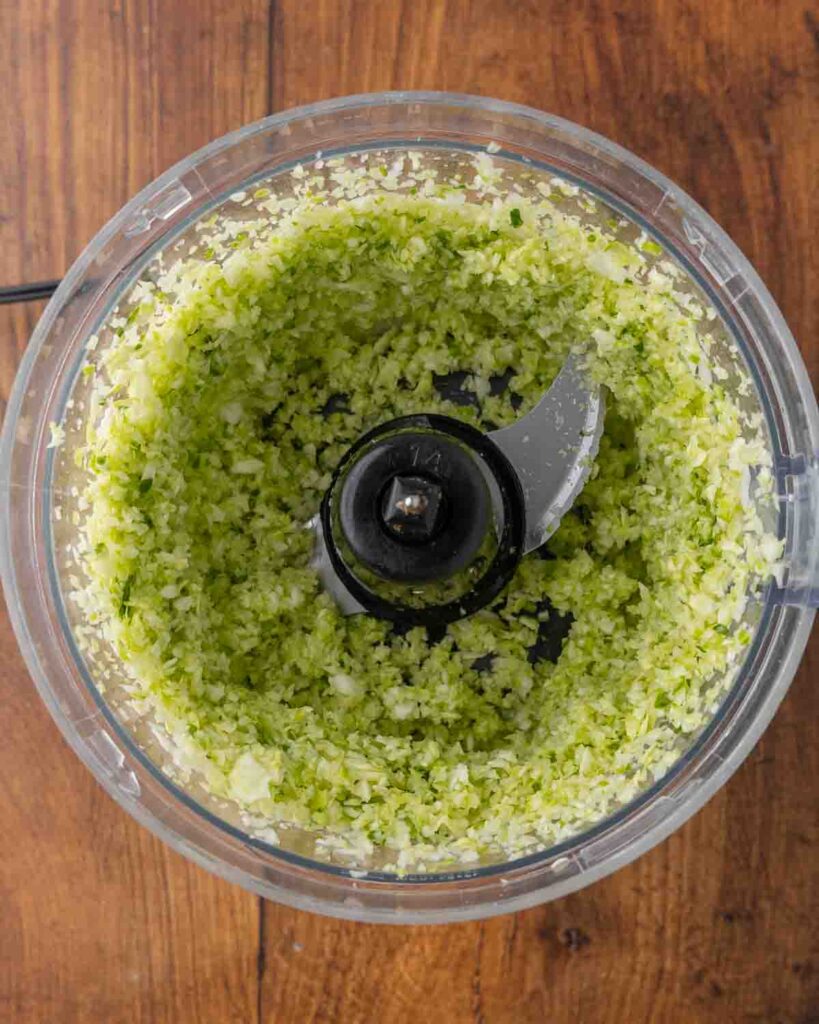 Bird's eye view of shredded cabbage in a food processor.