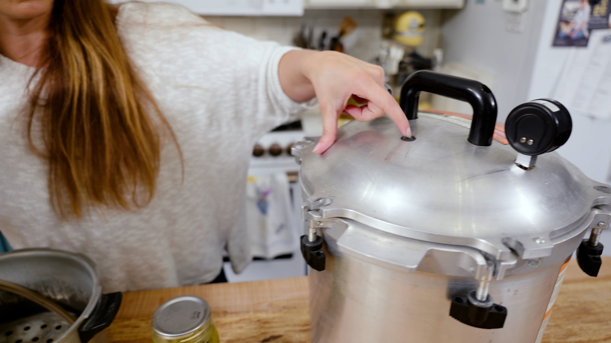 A woman pointing to the safety gasket on a pressure canner.