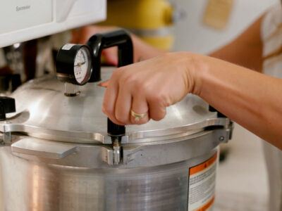 A woman tightening the latches on the lid of a pressure canner.