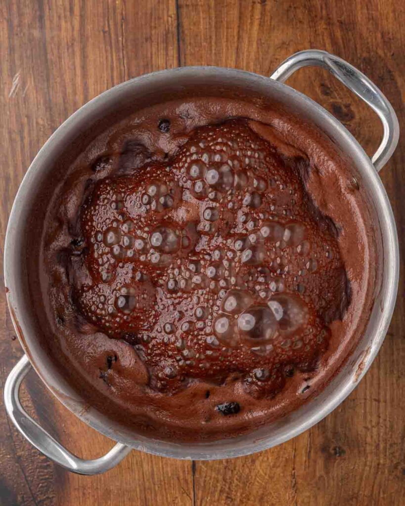 Chocolate cherry sauce boiling in a large saucepan.