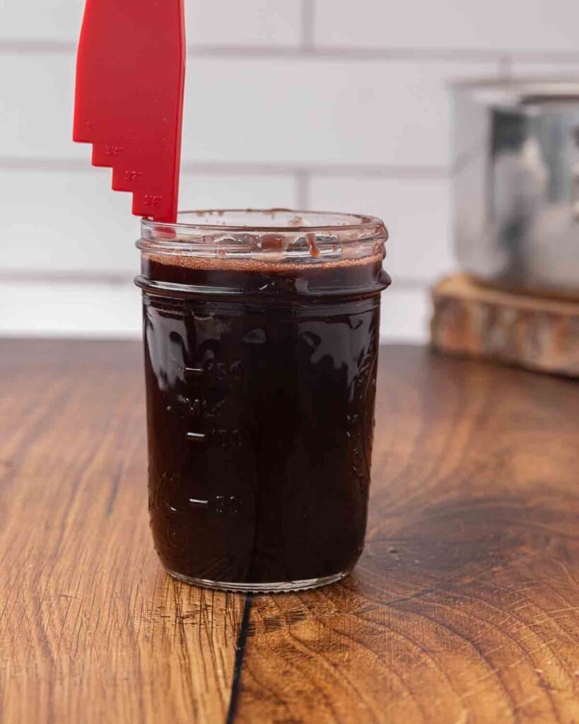 A headspace tool measuring a chocolate cherry sauce in a canning jar.