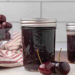 Jars of chocolate cherry sauce sitting on a counter.