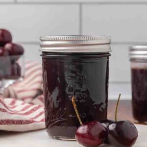 Jars of chocolate cherry sauce sitting on a counter.