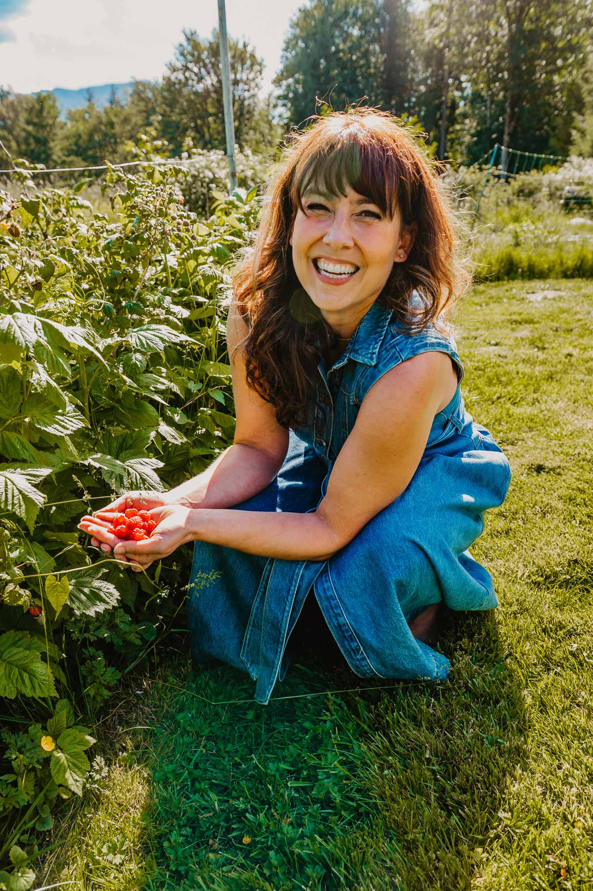 A woman picking raspberries.
