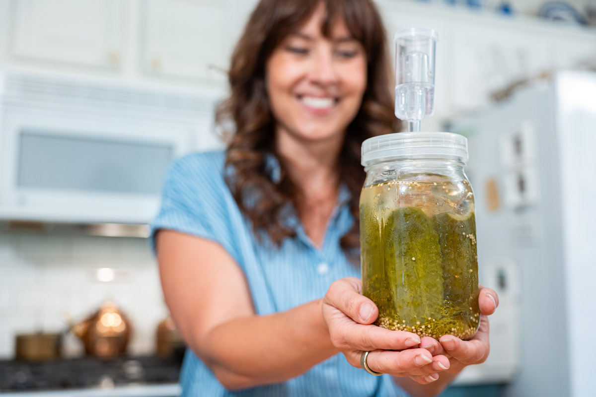 A woman holding a jar of fermented pickles.