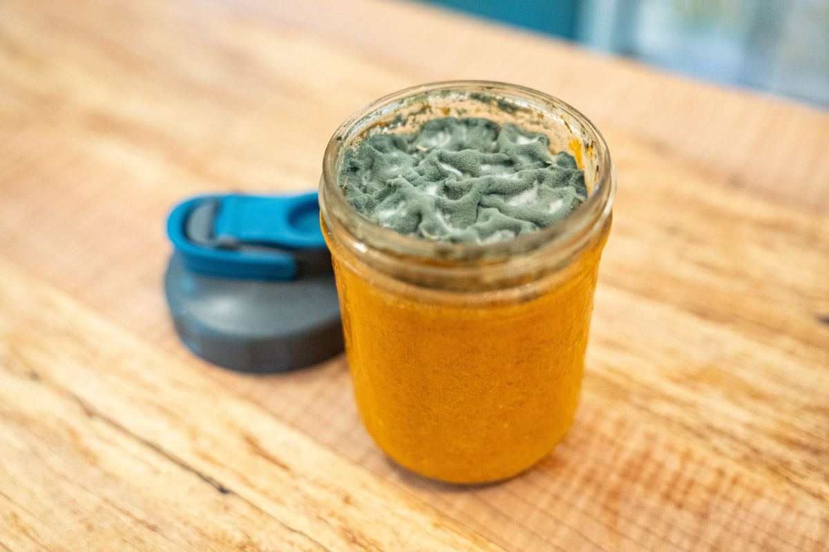 A jar of fermented hot sauce that's moldy on top.